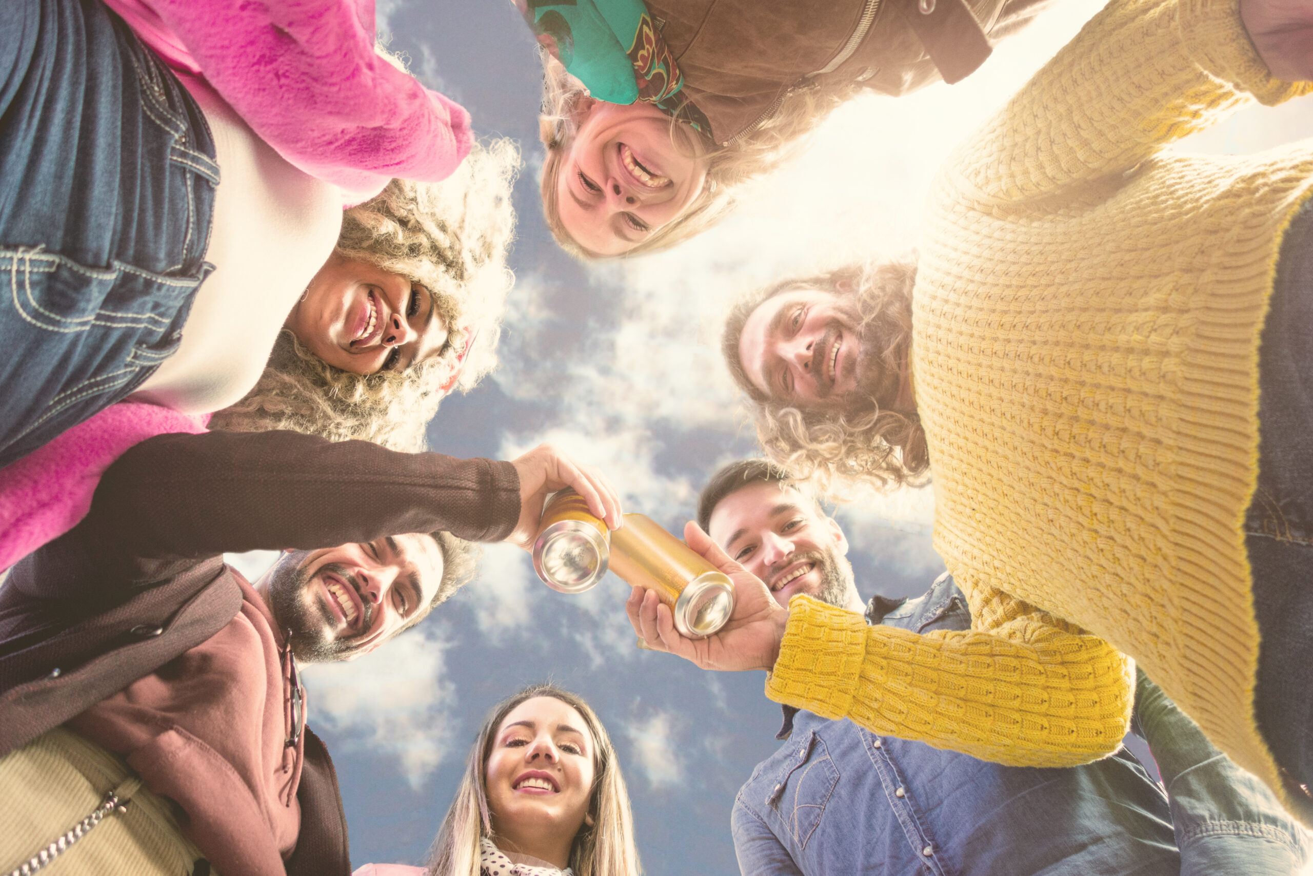 Group of diverse friends enjoying wellness outdoors, toasting with CBD and THC-infused beverages from The Specialty Club.